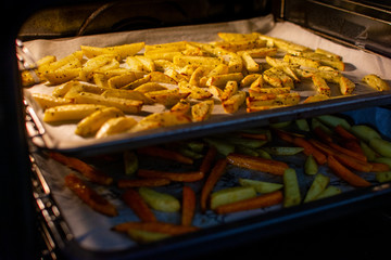 Home made french fries, cut potatoes with oregano sprinkle on the baking paper. View from inside the oven. Healthy vegan and vegetarian fast food.