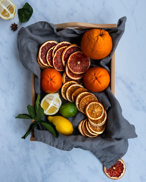 Top view of a wooden basket with fresh oranges and dried oranges on a gray background