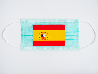 Spanish flag is on a medical mask on a white background. Coronavirus in the Spain. close-up. the view from the top.