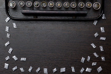 Typewriter, and metal letters, lie on a wooden table in the form of a frame
