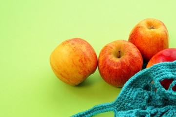 reusable shopping String bag, open netted bag with fresh apples. Mesh shopping bag with fruits on green background. Zero waste, Eco-friendly shopper and Ecology concept. View from above, plastic free
