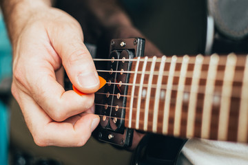 Black electric guitar close-up - male hand playing a pick on strings - downstroke and upstroke - a...