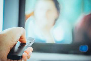 Fernsehfernbedienung in der Hand des Mannes. Der Mann wechselt den Kanal.