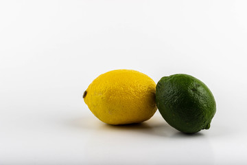 One delicious and sour yellow lemon and green lime lie on a table against a white background.