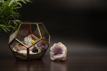 A miniature garden of stones and crystals in a glass terrarium and the raw mineral amethyst on a...