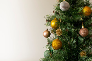 Close up of a beautiful Christmas tree with yellow, golden and rosé balls, with space for text