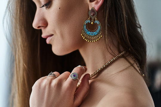 Stylish sensual boho chic woman wearing big earrings, gold necklace and silver rings with stone. Fashionable indian hippie gypsy bohemian outfit with jewelry details accessories