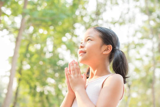 cute little girl hands praying to god with the bible in the morning on nature background.  little asian girl hand praying for thank god. copy space. spirituality and religion faith hope concept.