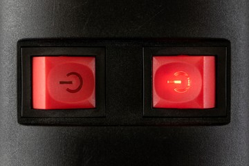 A close up portrait of two red on off safety switches of a power strip with a light in them to...