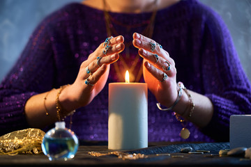Fortune teller woman using burning candle flame for spell, witchcraft, divination and fortune...