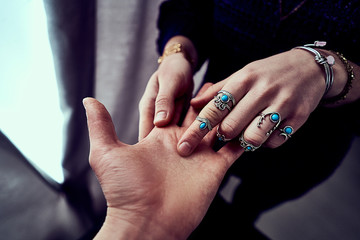 Fortune teller woman wearing silver rings with turquoise stone and bracelets reads palm lines...