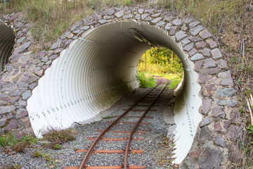 old stone narrow gauge rail train tunnel. Light at the end of the tunnel