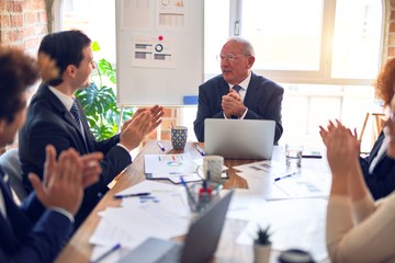 Group of business workers smiling happy and confident in a meeting. Working together looking at presentation using board and laptop applauding at the office.