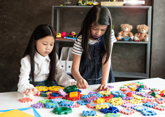 Two little girl are playing plasticine together,with interested feeling,at home studio,Lens flare effect,blurry light around