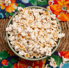 top view of  big bowl  full of popcorn  on the straw table