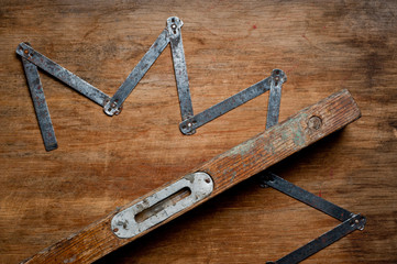 Old vintage carpentry level and a lazy bone of the last century extracted from a chest in a grandfather's workshop. Background for craftsmanship and manual labor.