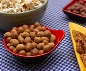 several bowls with  peanuts  and popcorn on the  table
