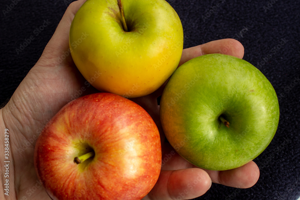 Poster three apples, one green and two red and yellow in the hand.