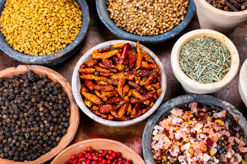 Indian spices collection, dried colorful condiment, nuts, pods and seeds and another spices in clay bowls