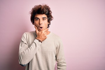 Fototapeta na wymiar Young handsome man wearing casual t-shirt standing over isolated pink background Looking fascinated with disbelief, surprise and amazed expression with hands on chin