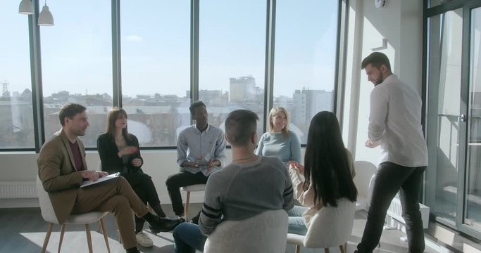 Team of successful businessmen welcomes a new employee and gets to know him during a morning conference in a spacious sunny room. Young mixed race team concept