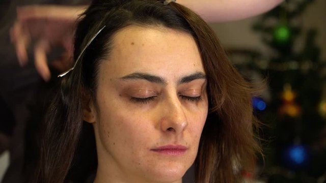 The stylist uses hairspray to fix the girl's hair when creating a hairstyle