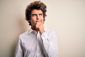 Young handsome businessman wearing elegant shirt standing over isolated white background with hand on chin thinking about question, pensive expression. Smiling with thoughtful face. Doubt concept.