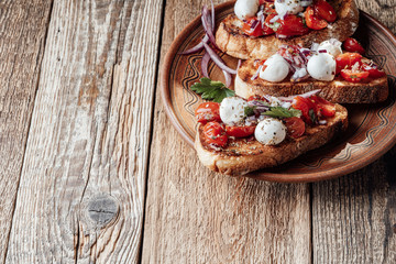 Tomato bruschetta with mozzarella in rural ceramic bowl