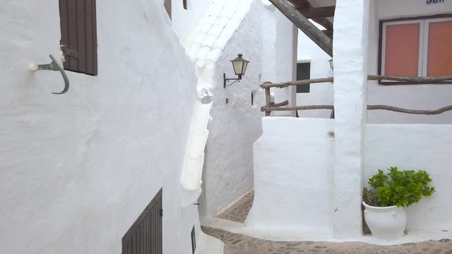 Walking trough Binibeca Vell, a narrow sidewalk natural labyrinth. Old traditional menorcan fishing village with white houses located on the coast of Menorca. Balearic Island, Spain.