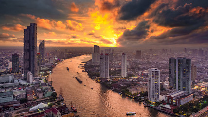 Fototapeta na wymiar Aerial view Bangkok City skyline and skyscraper on Sathorn Road business and financial in Bangkok downtown, Taksin Bridge over Chao Phraya River, Bangkok, Thailand at sunset.