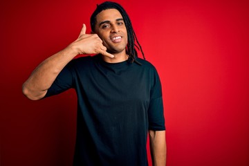 Young handsome african american afro man with dreadlocks wearing casual t-shirt smiling doing phone gesture with hand and fingers like talking on the telephone. Communicating concepts.