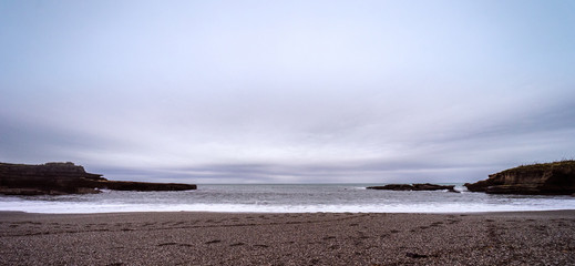 Beautiful panoramic shot of a pebbles beach taken on a cloudy winter day at Truman Track, New Zealand