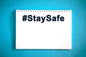 Hashtag STAYSAFE text on a notepad on a blue background