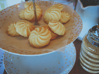 Cookies on dish with a sugar pot on the wooden table.
