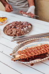 Process of making kebab. Meat on skewer. Cooker follow hygiene and use gloves. Mixed grill. Traditional arabic dish. Family dinner. Real photos of cooking