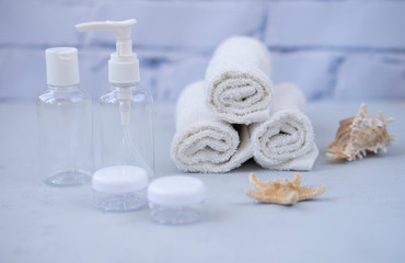Plastic containers. Spa composition, recreation and hospitality. Beauty and skin care concept.  Plastic bottles, lens containers and white towels on a light background
