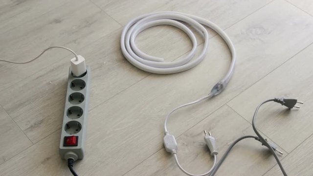Man plug in socket Electrical Surge Protector and turn on the led strip.