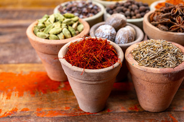 Indian spices collection, dried colorful condiment, nuts, pods and seeds and another spices in clay bowls