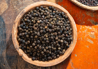 Indian spices collection, dried black peppercorns  and another spices in clay bowls