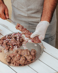 Process of making kebab. Meat on skewer. Cooker follow hygiene and use gloves. Mixed grill. Traditional arabic dish. Family dinner. Real photos of cooking