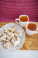 Close-up. A plate of fresh cinnamon rolls with butter cream.