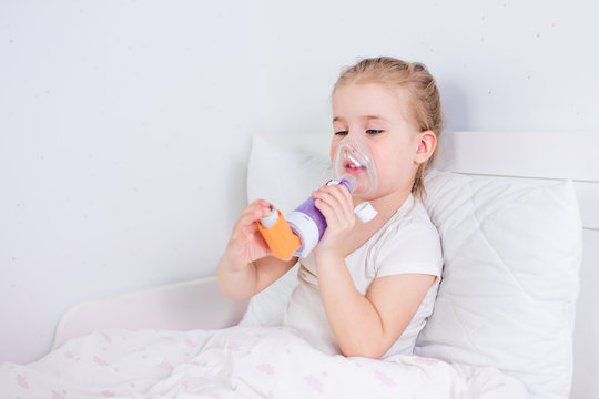 Sick little girl with asthma medicine lying in bed. Unwell kid with chamber inhaler for cough treatment. Flu season. Bedroom or hospital room for young patient. Healthcare and medication.
