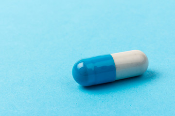 Pills isolated on blue background. Medical drug capsule. Concept of coronavirus