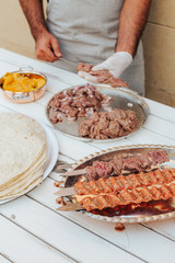 Process of making kebab. Meat on skewer. Cooker follow hygiene and use gloves. Mixed grill. Traditional arabic dish. Family dinner. Real photos of cooking