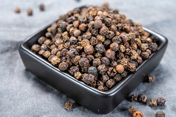 Bowl with dried black round peppers condiment