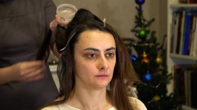 The stylist uses lipstick to fix the hair on the back of the girl's head