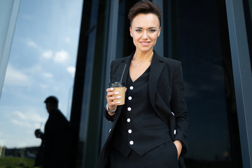 Female in office suit made an appointment and is waiting for colleague and drinks coffee