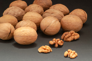 Whole and chopped walnuts on a black background. Place for text. Copy space