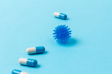 Pills isolated on blue background. Medical drug capsule. Concept of coronavirus