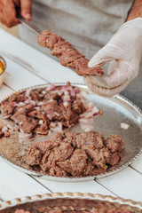 Process of making kebab. Meat on skewer. Cooker follow hygiene and use gloves. Mixed grill. Traditional arabic dish. Family dinner. Real photos of cooking